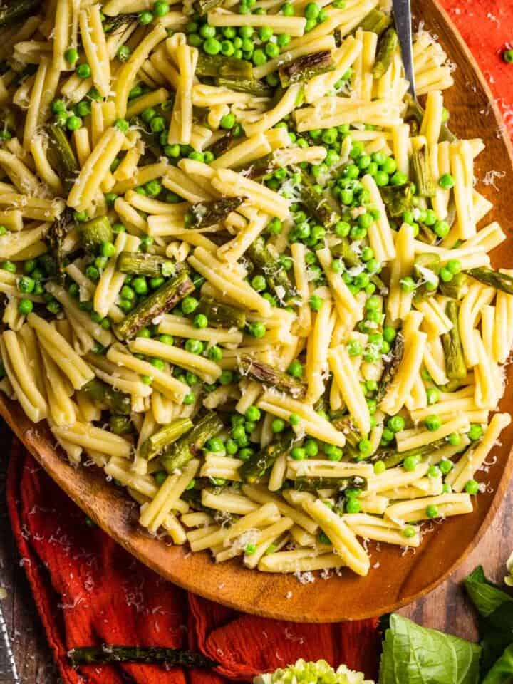 wooden tray with casarecce pasta with roasted asparagus, peas and grated cheese