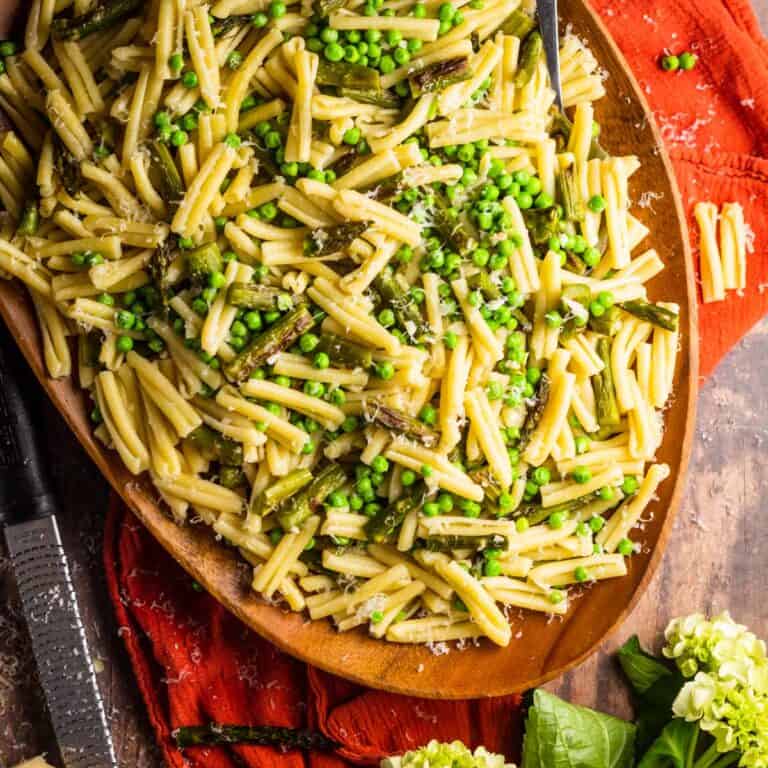 wooden tray with casarecce pasta with roasted asparagus, peas and grated cheese