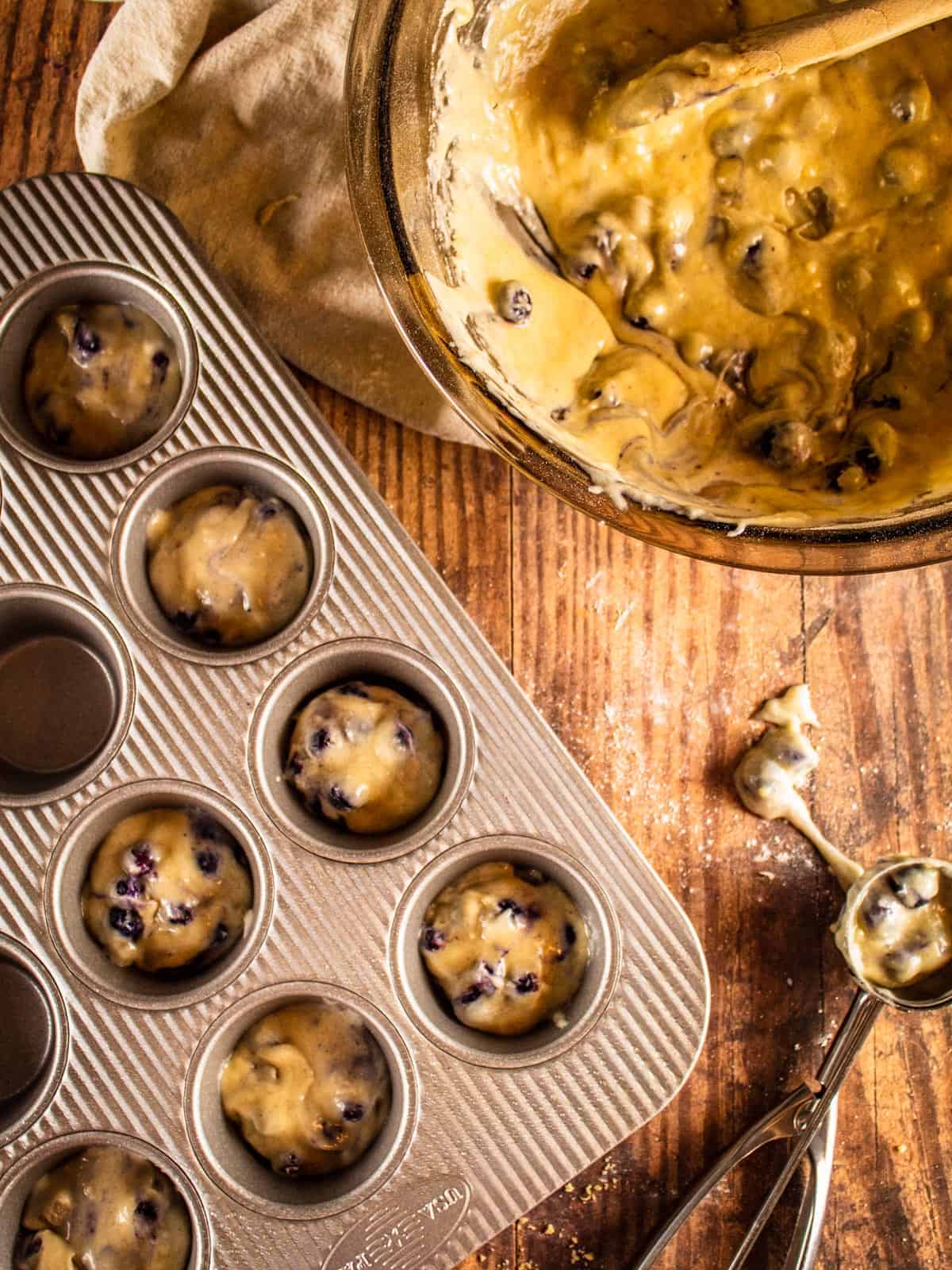 muffin tin with blueberry muffin batter in it
