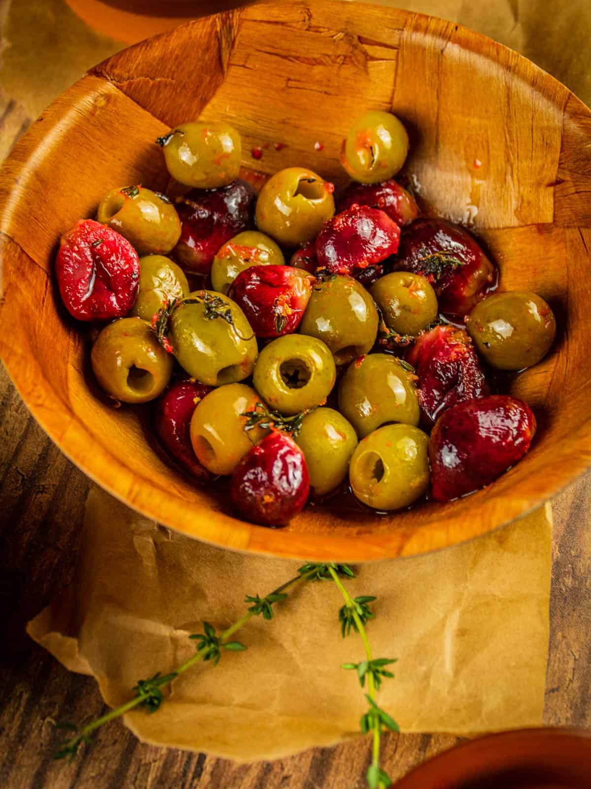 wooden bowl of red roasted grapes and green roasted olives
