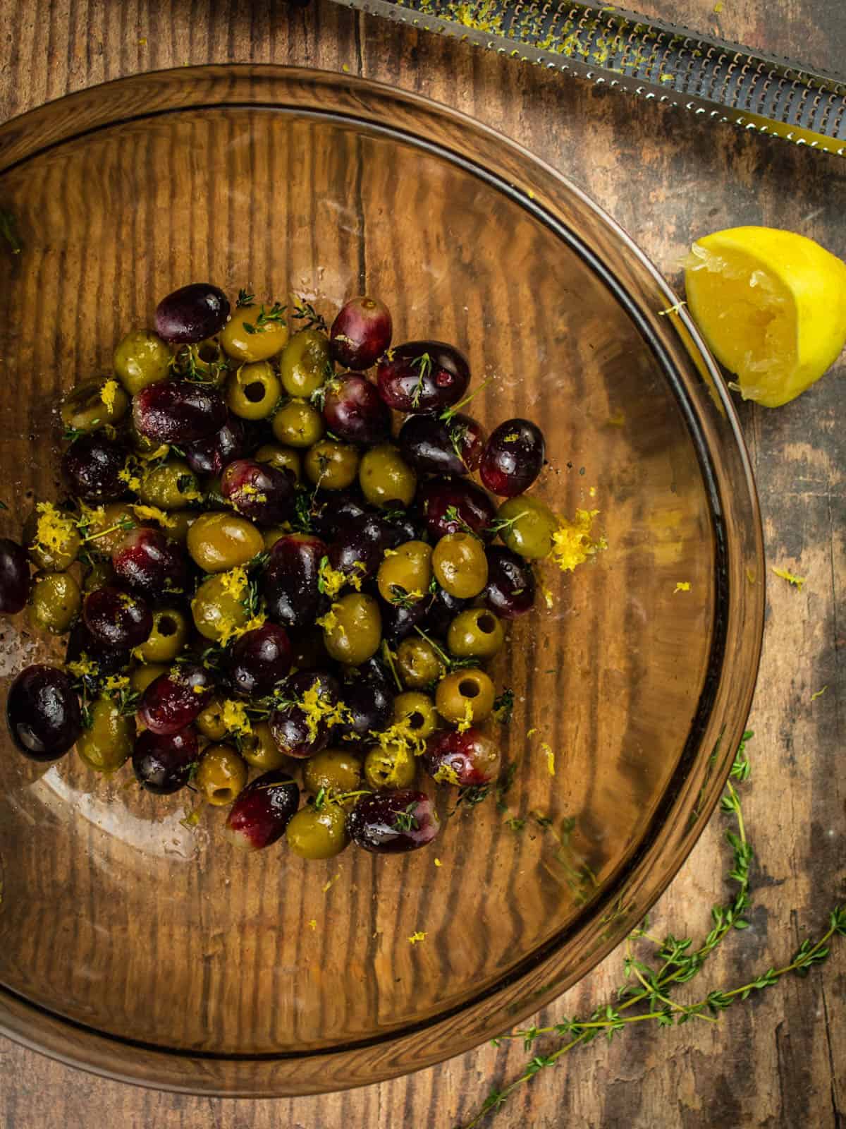 grapes, olives, lemon zest, thyme and olive oil in a bowl
