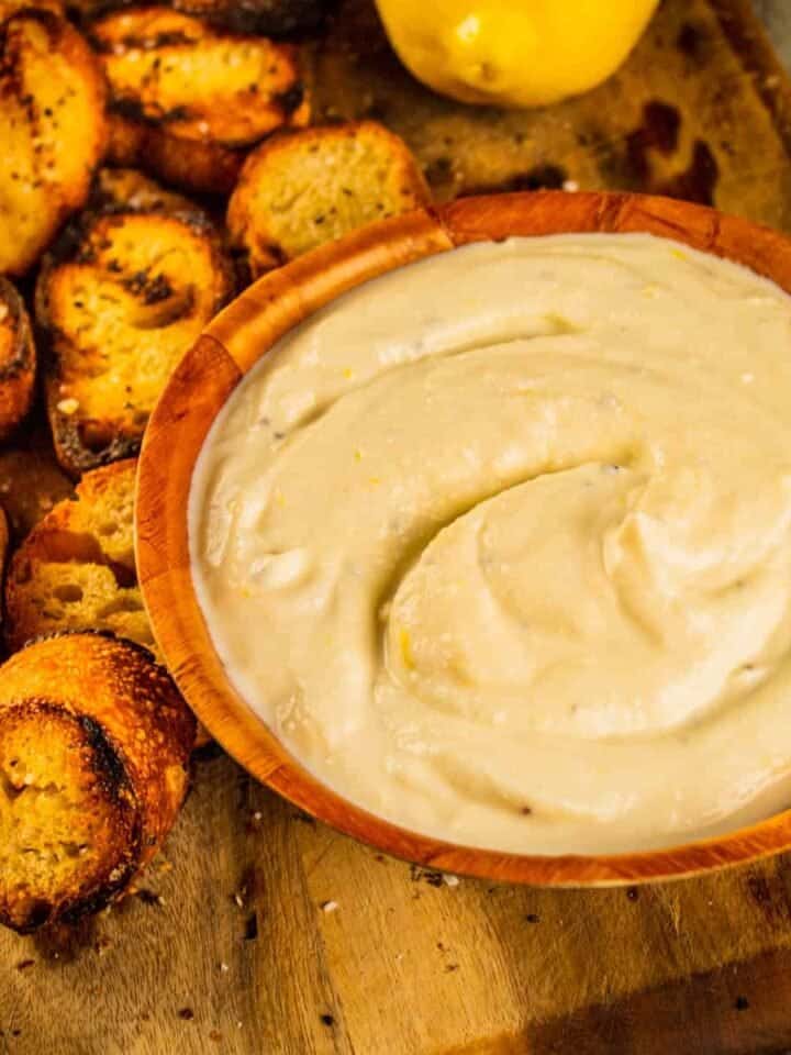 whipped ricotta spread in a wooden bowl with grilled pieces of bread next to it