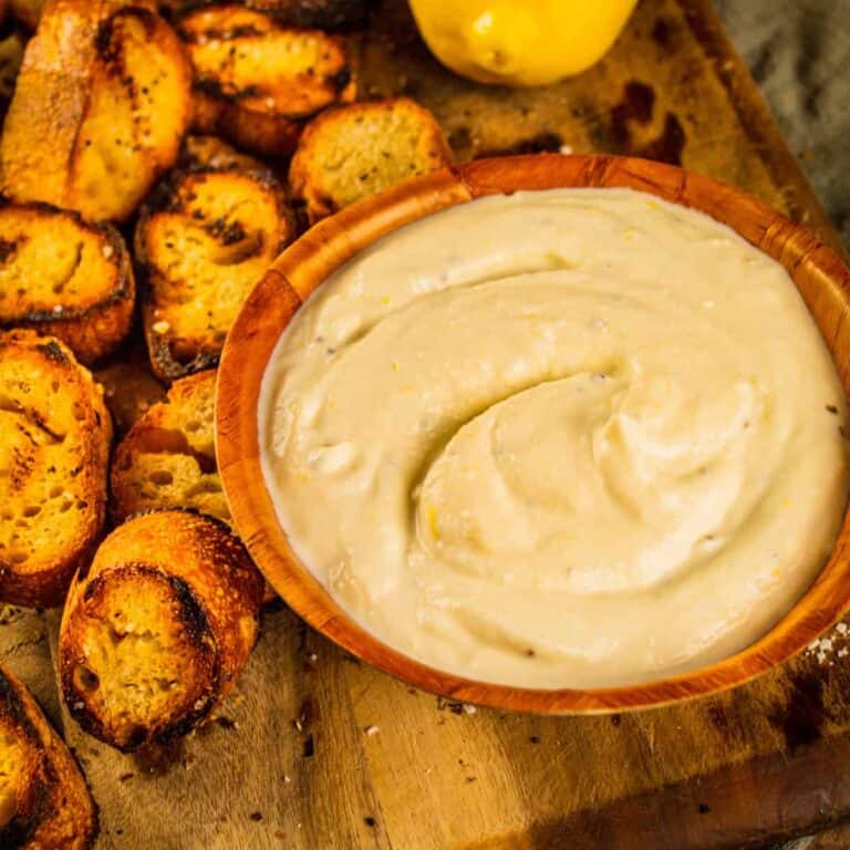 whipped ricotta spread in a wooden bowl with grilled pieces of bread next to it