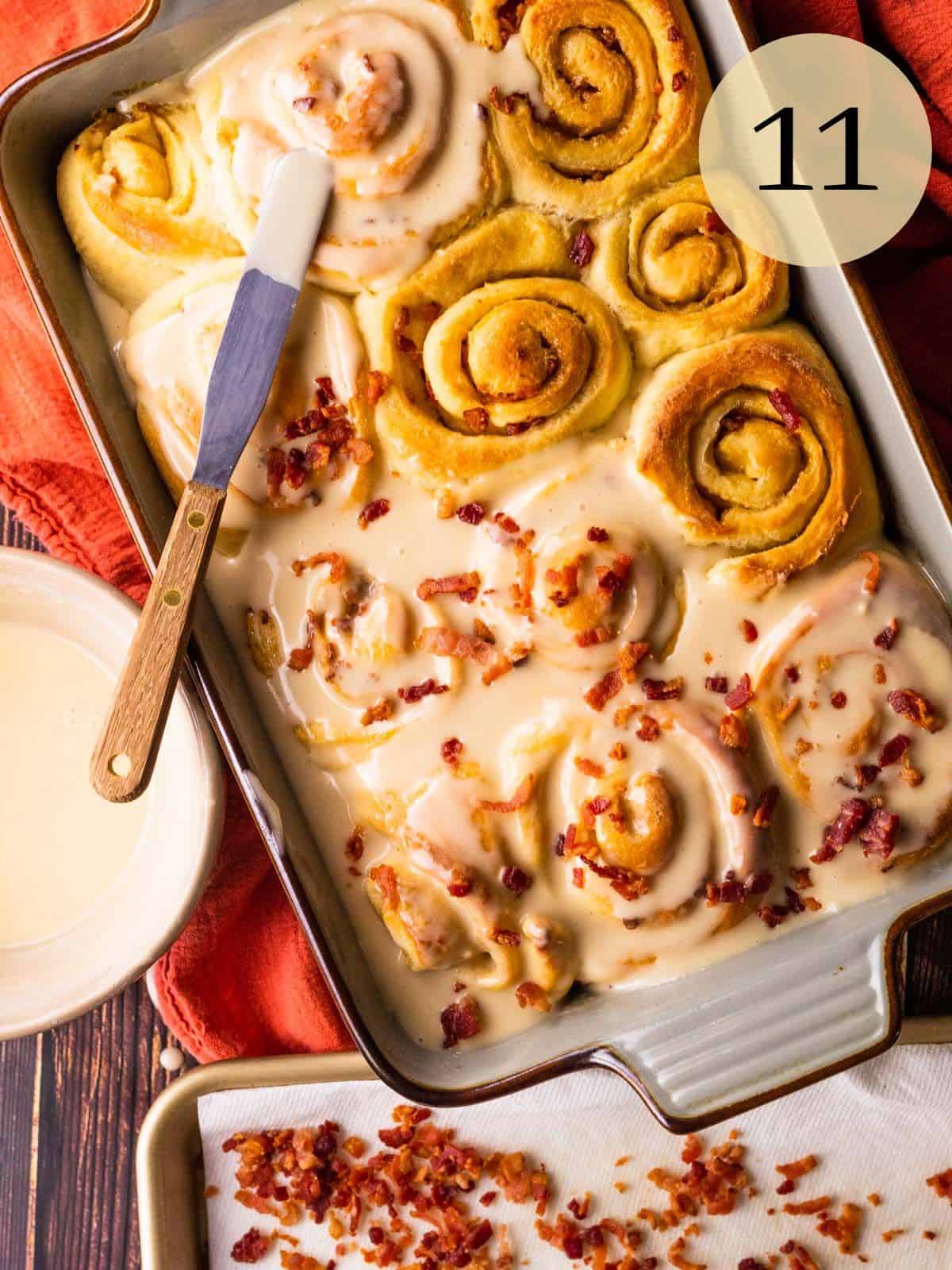 baked cinnamon rolls partially frosted with some crispy bacon pieces on it.