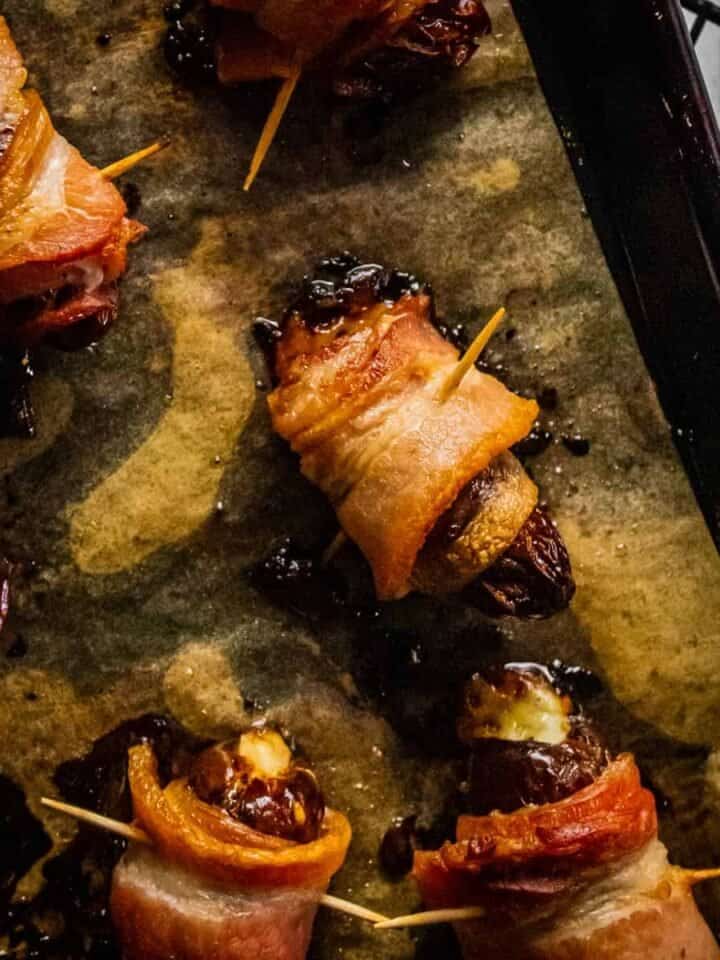 bacon wrapped dates stuffed with cheese on a sheet pan