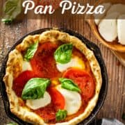 pizza in a cast iron pan with tomato, mozzarella and basil.