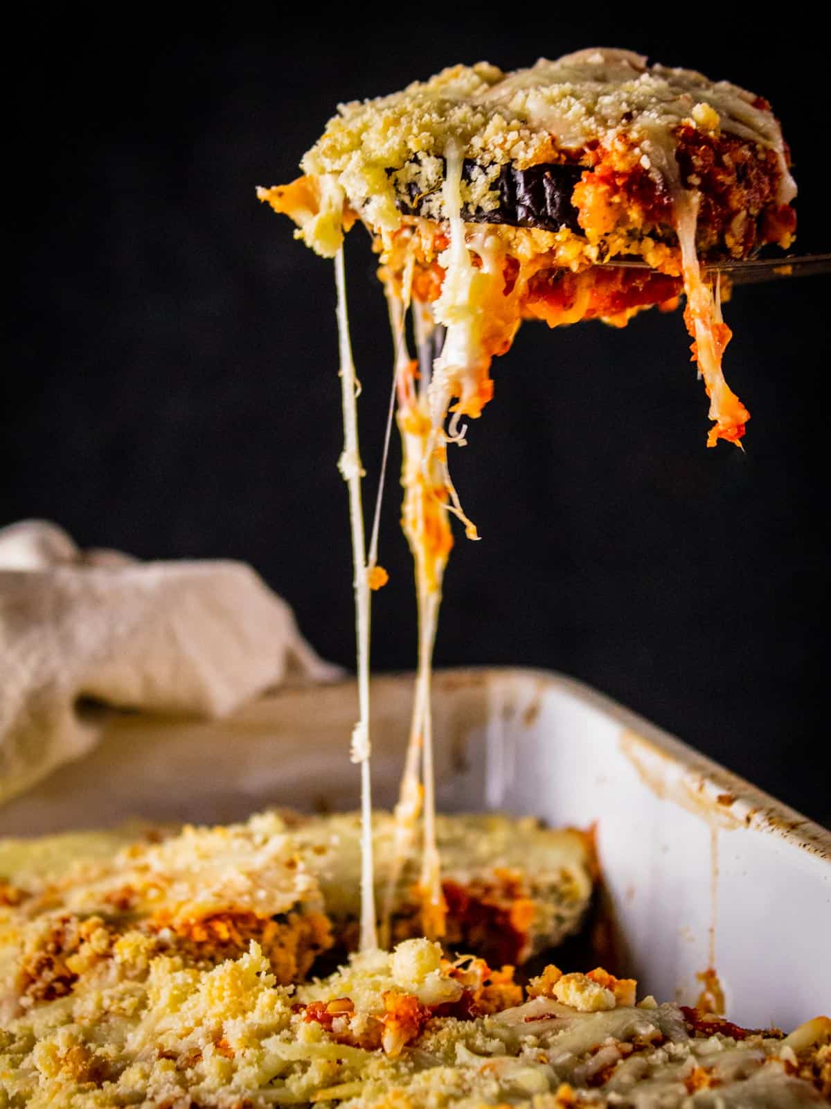 eggplant slice on a serving spatula with cheese pulling from it