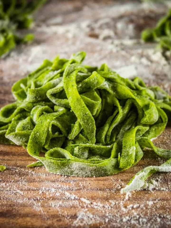 pile of uncooked homemade spinach fettuccine on a table