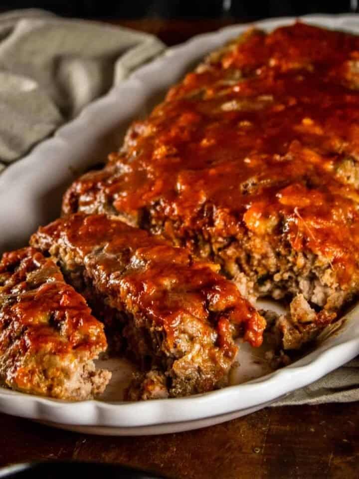 partially sliced italian meatloaf on a white platter