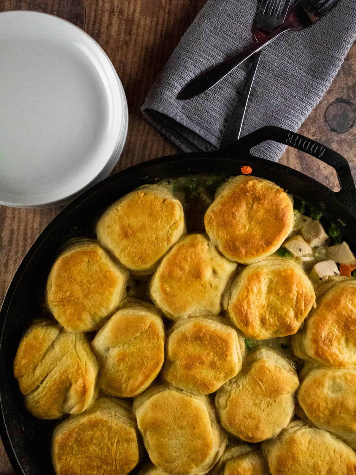 cast iron skillet of cooked chicken pot pie with biscuits
