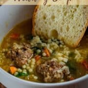 slice of french bread in a bowl of soup with meatballs.