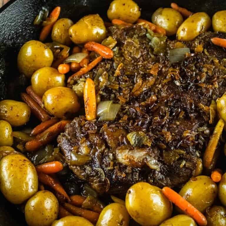 cooked pot roasted in a cast iron skillet with potatoes and carrots