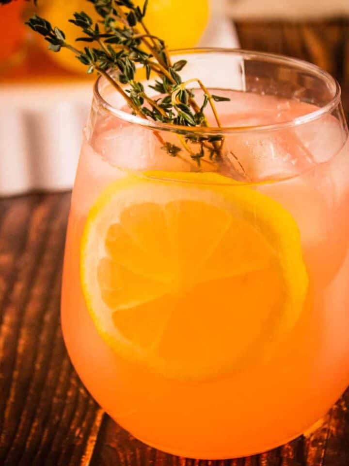 glass with pink lemonade, lemon wheel and fresh thyme sprig