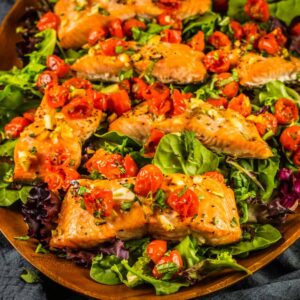 salmon filets on spring salad topped with roasted tomatoes, garlic and fresh basil.