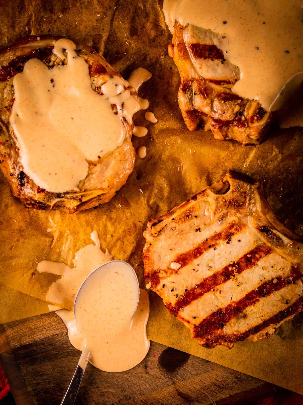 grilled pork chops on a tray covered in white bbq sauce.