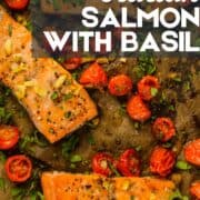 roasted salmon filets with garlic, tomatoes and basil on a sheet pan.