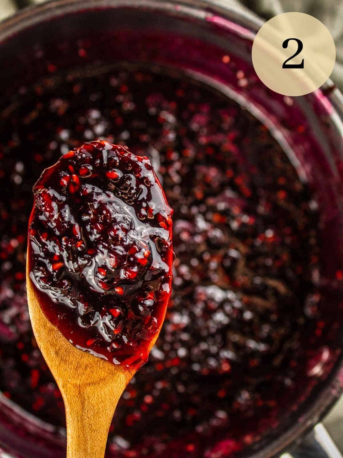 wooden spoon holding a scoop of homemade blackberry jam