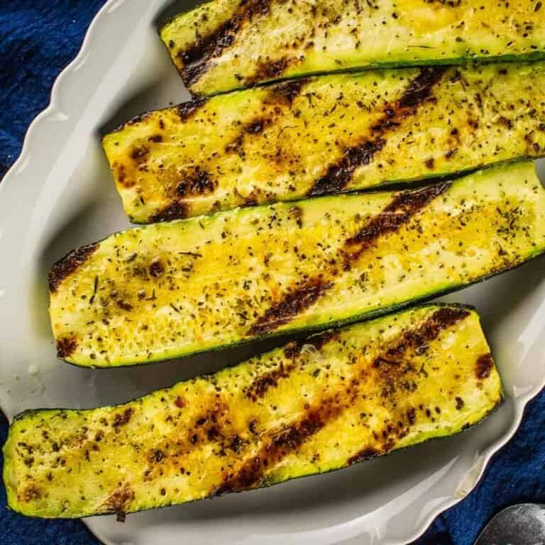 grilled zucchini halves on a white tray