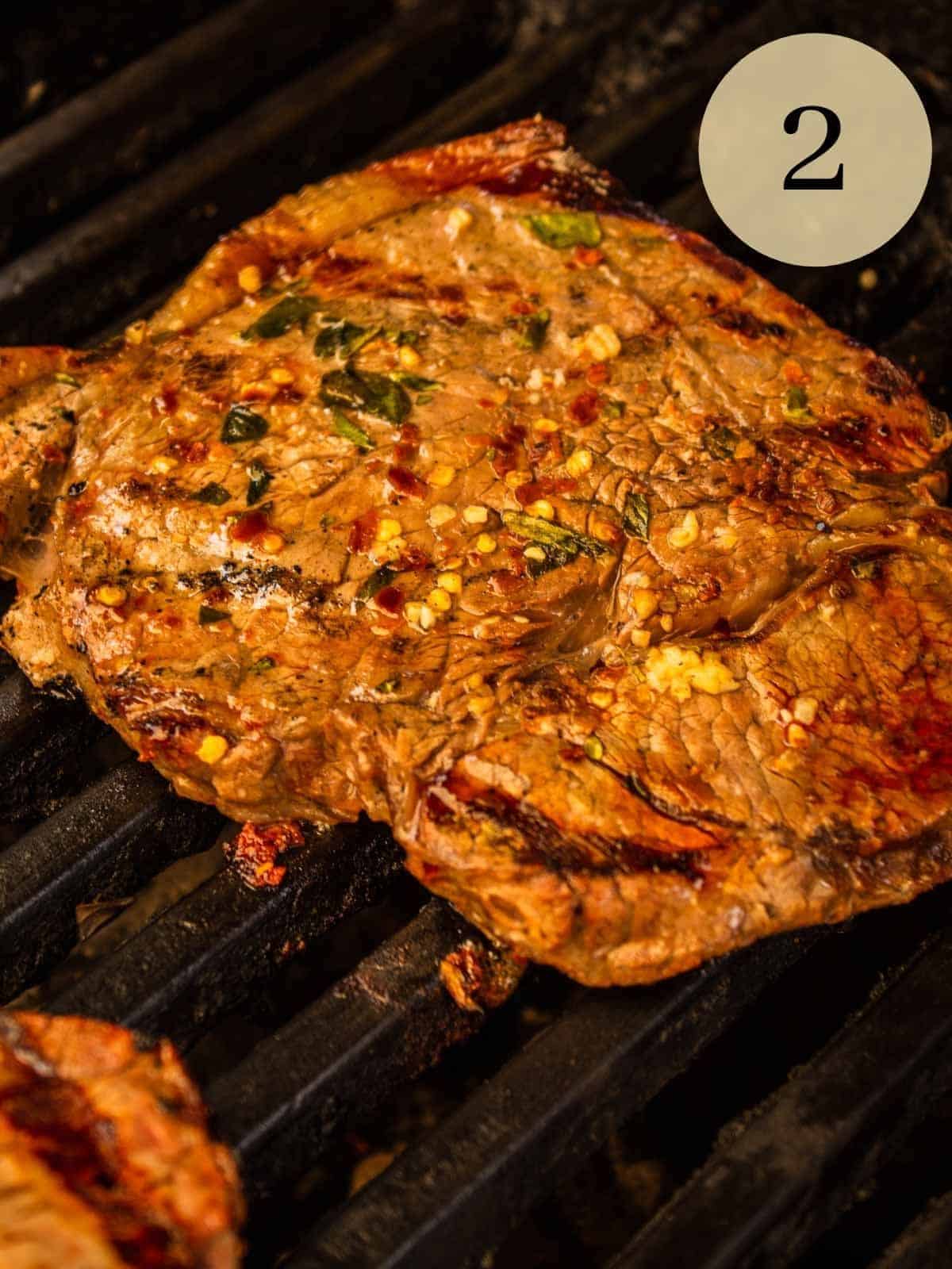marinated and seasoned italian steak cooking on the grill.