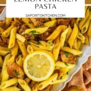 penne pasta with lemon chicken, fresh parsley and lemon slices on a white platter