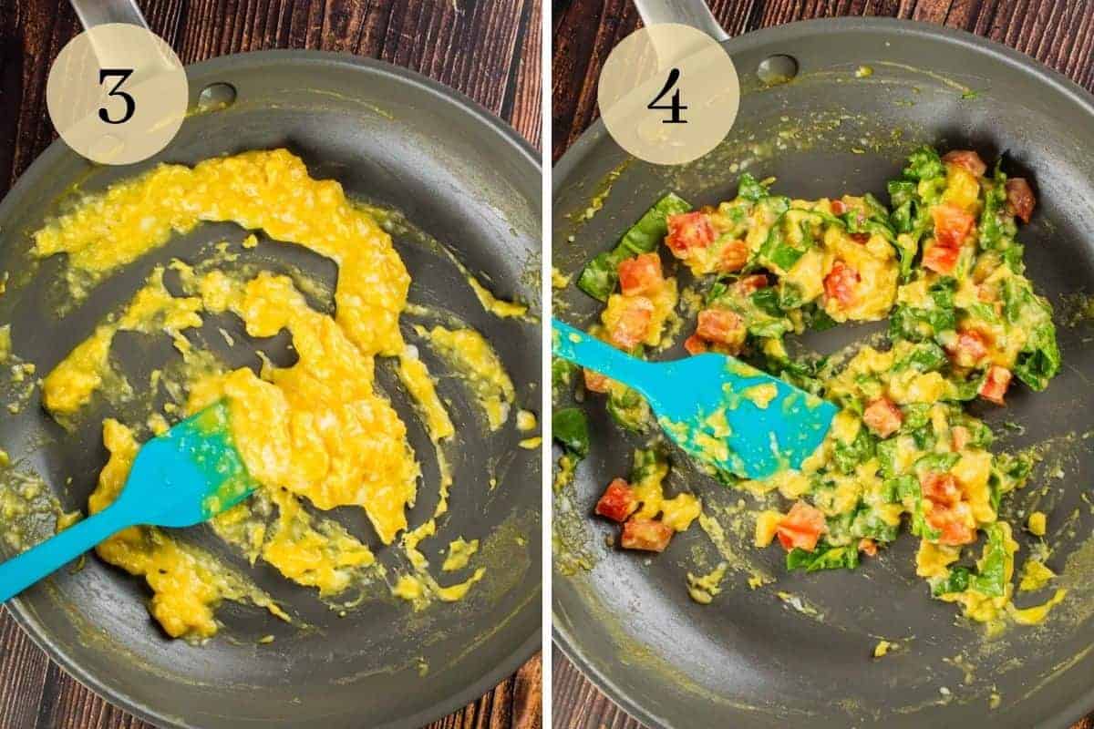 scrambled eggs cooking in a pan and a rubber spatula stirring in  spinach and tomatoes.