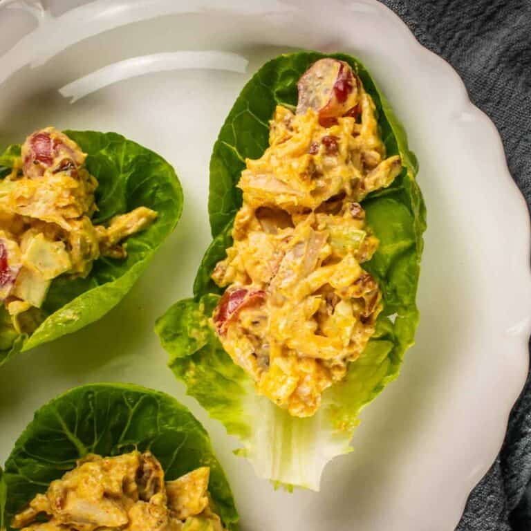 chicken salad with grapes and pecans on lettuce cups on a white platter