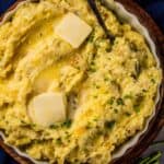 mashed potatoes in a circle dish topped with butter and chopped chives