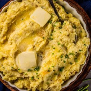 mashed potatoes in a circle dish topped with butter and chopped chives