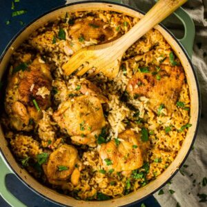 chicken and rice in a dutch oven pot with a wooden spoon.