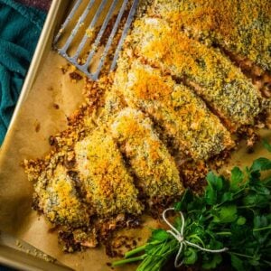 panko crusted large salmon fillet partially cut on a sheet pan