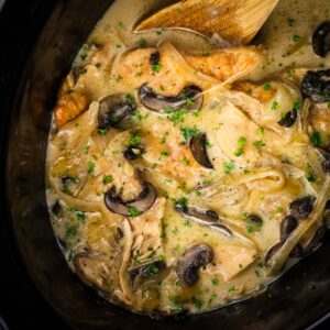 creamy chicken marsala in a crock pot with a wooden spoon in it