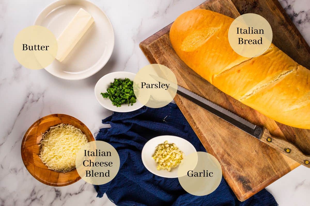 butter, parsley, garlic, cheese and italian bread on a cutting board with a knife.