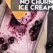 ice cream cone with black cherry ice cream sitting in a pan of ice cream with cherries around.