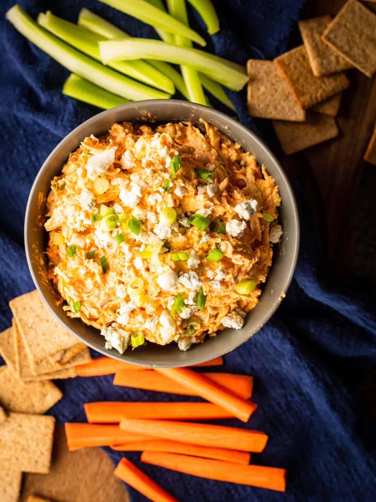 buffalo chicken dip in a bowl topped with blue cheese and green onions. 