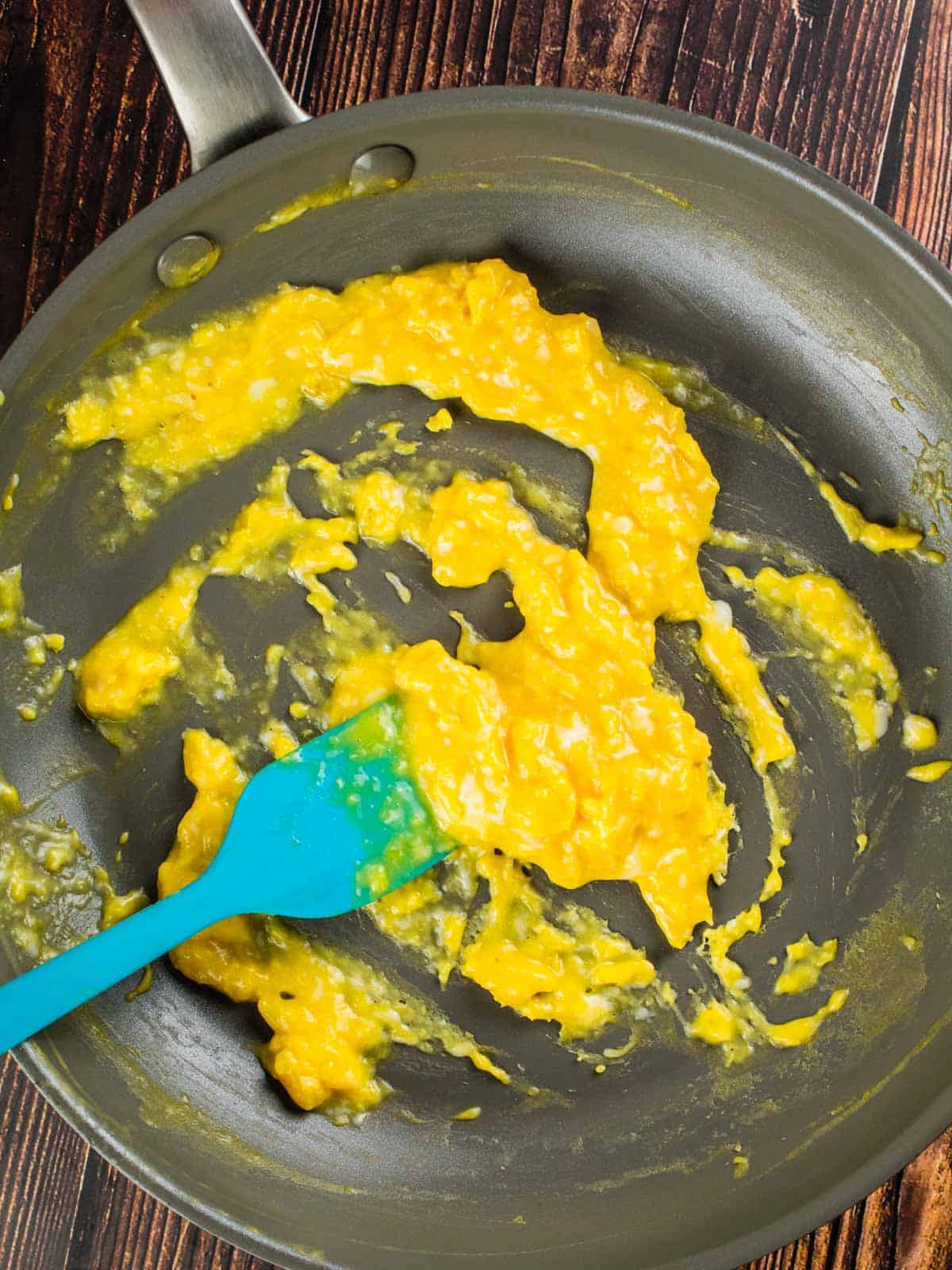 scrambled eggs cooking in a pan with a silicone spatula.