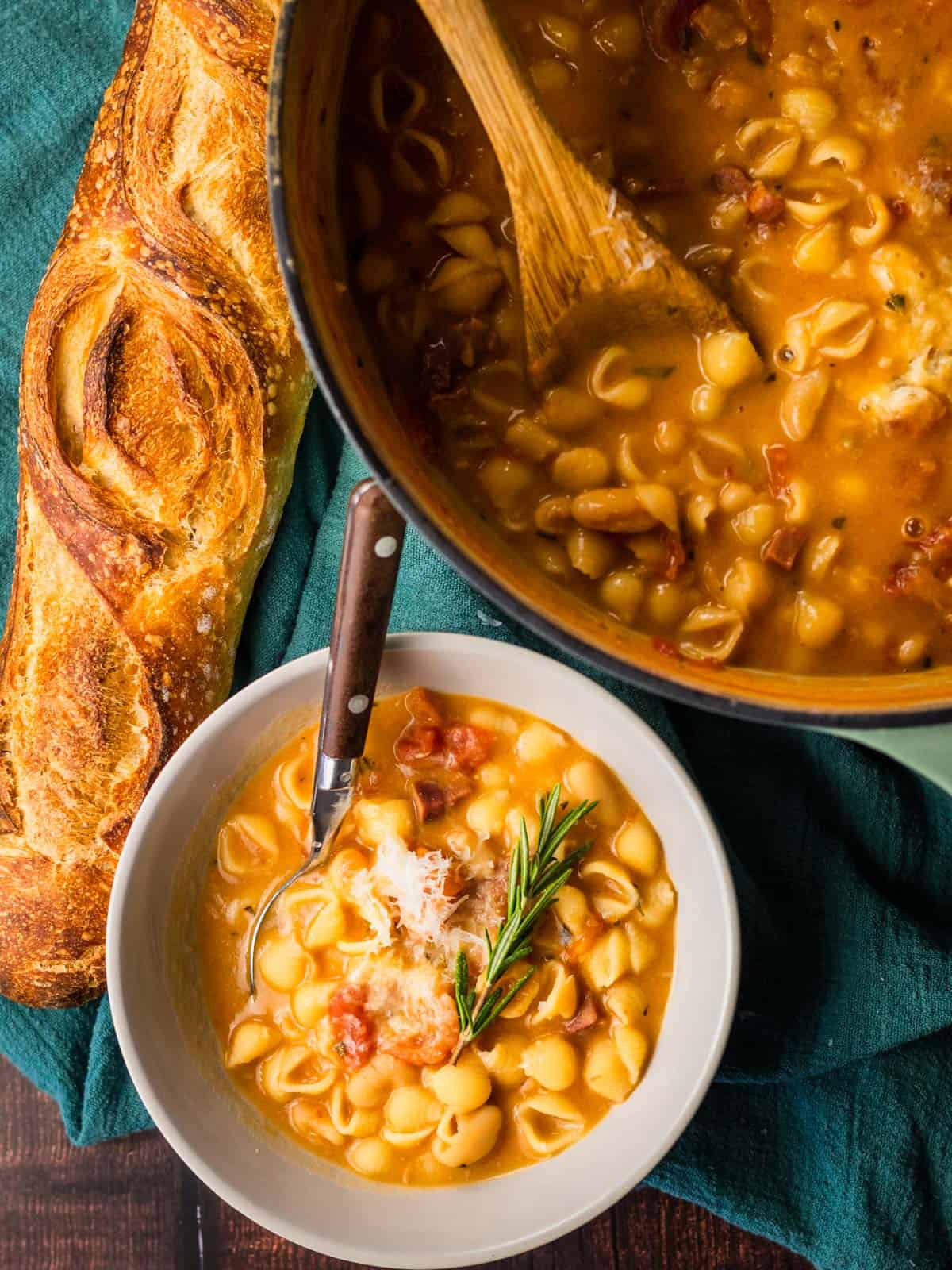 dutch oven pot and bowl of pasta fagioli with a loaf of bread next to it.