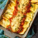 pan of crepe italian manicotti topped with sauce, grated cheese and chopped parsley.