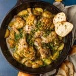 roasted chicken potatoes and peas in a sauce with bread in cast iron skillet.