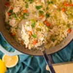 chicken orzo soup in a ladle over a large pot of soup.