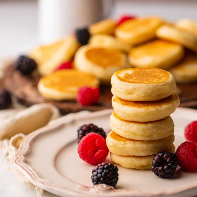 stack of silver dollar pancakes on a plate with fresh berries.