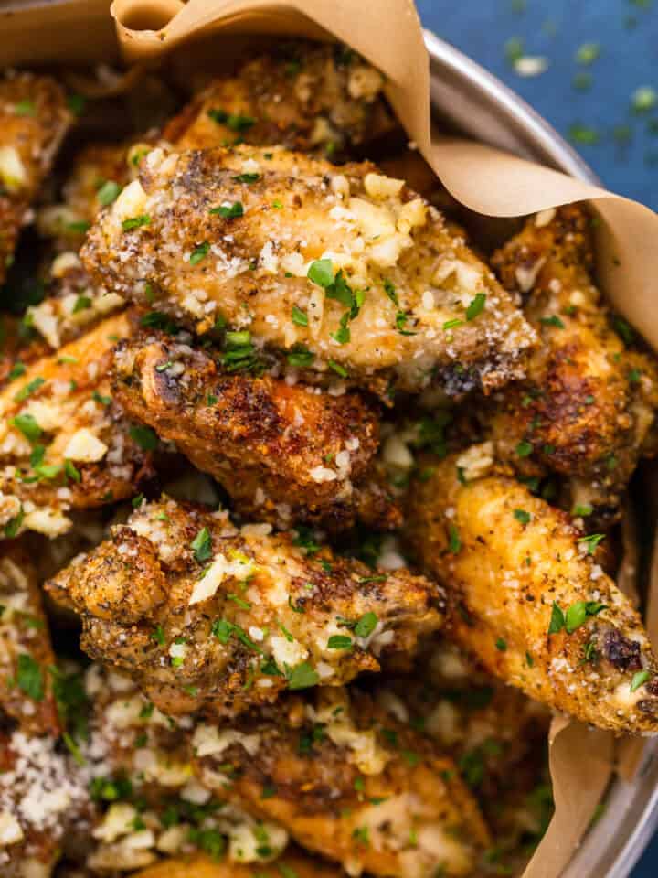 crispy chicken wings in a dish with garlic butter and parmesan cheese and parsley.