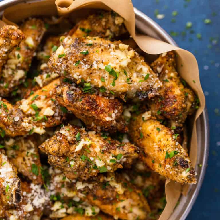 crispy chicken wings in a dish with garlic butter and parmesan cheese and parsley.