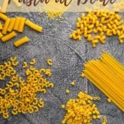 piles of different pasta shapes sitting on a table.
