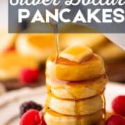 stack of mini pancakes on a plate with a pat of butter and syrup pouring over the top of them.