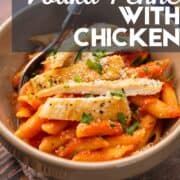 sliced chicken on to of penne with vodka sauce in a bowl with a fork.