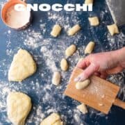 hand rolling gnocchi dough on a board.