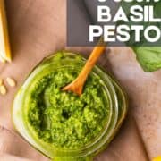 basil pesto in a jar with a wooden spoon.