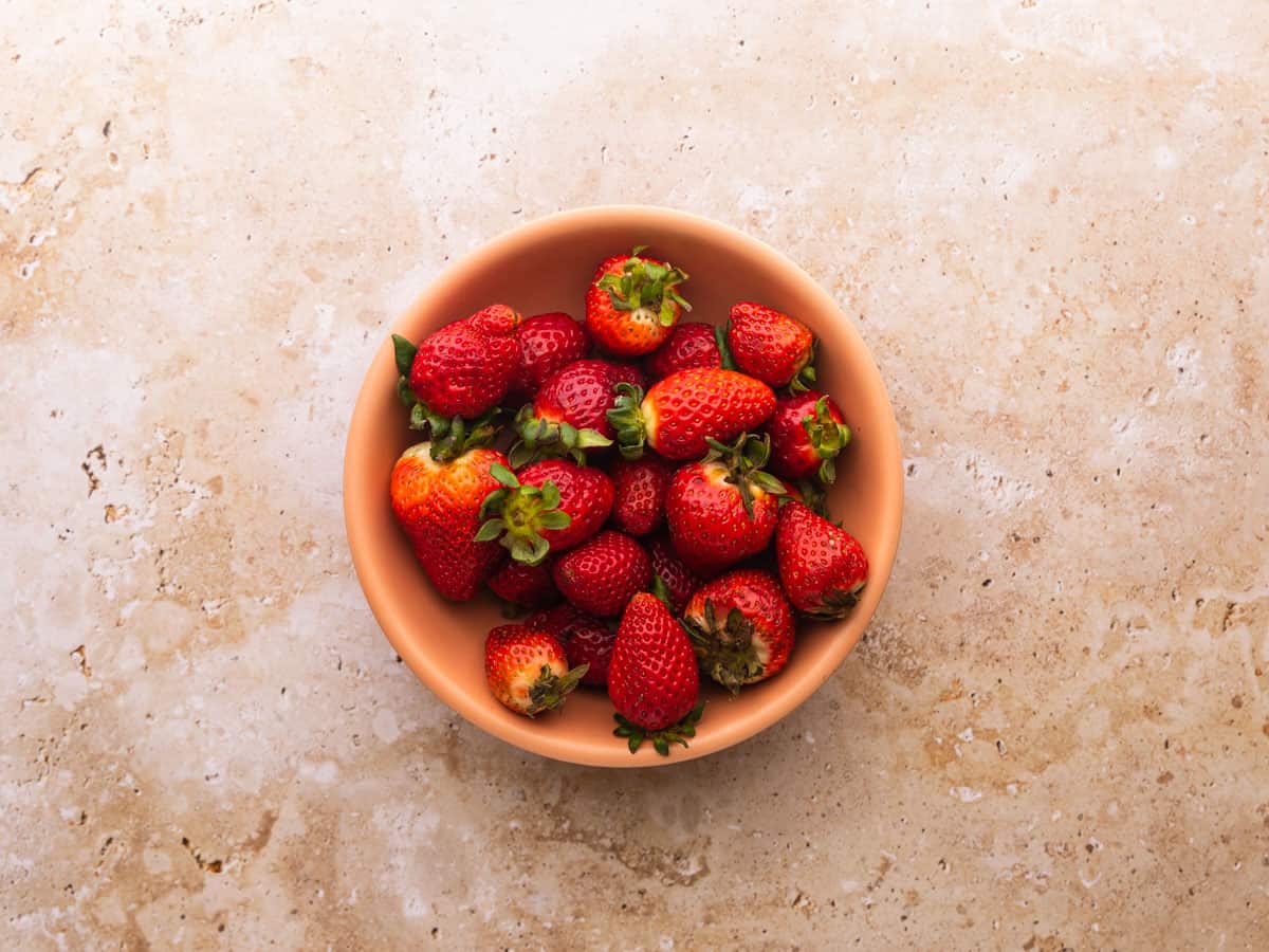 Fresh whole strawberries in a bowl on a table.