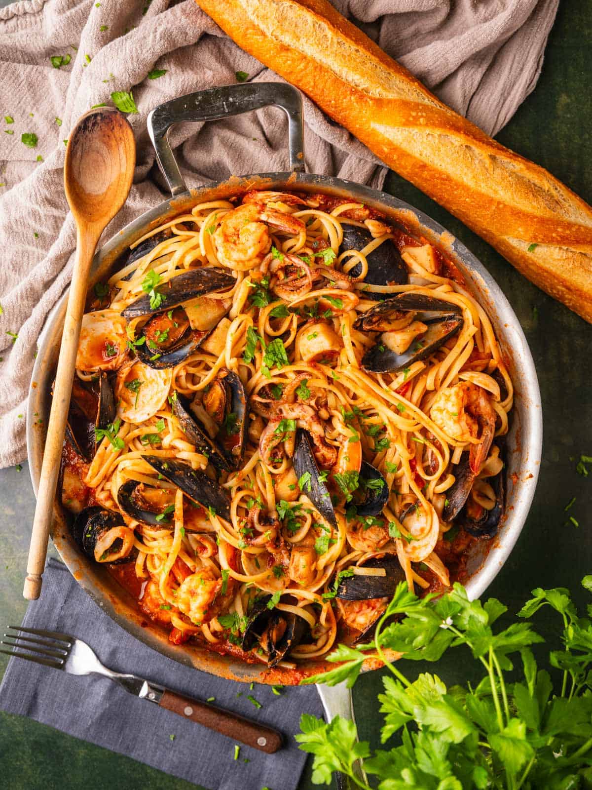 linguine with seafood in a tomato sauce in a skillet with bread next to it.
