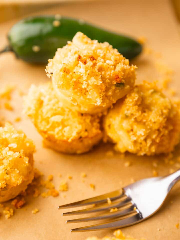crispy mac and cheese bites stacked on each other next to a jalapeno and a fork.